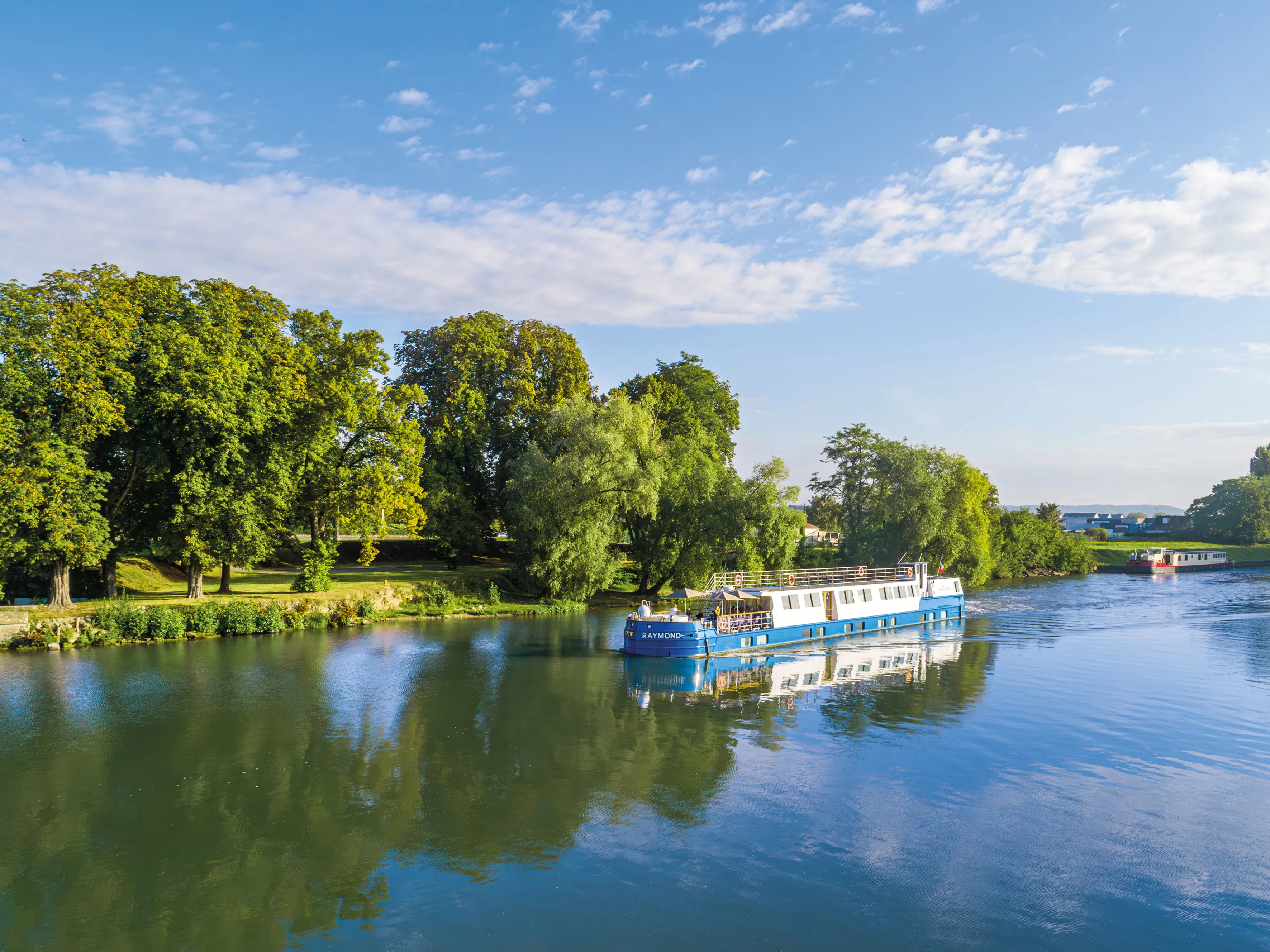 Péniche CroisiEurope naviguant sur un canal bordé d’arbres